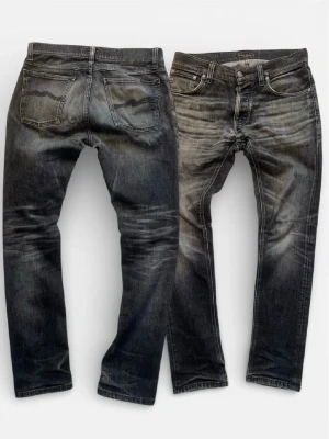 Svarta slim fit jeans från Nudie - Snygga svarta slim fit jeans från Nudie med slitna detaljer och klassisk femficksdesign. Jeansen har en cool tvätt med ljusare partier och Nudies ikoniska broderi på bakfickorna. Tillverkade i bomull med en skön stretch för extra komfort. FAST PRIS