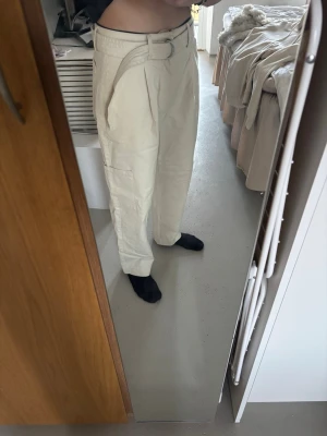 Beiga cargobyxor med bälte - Säljer ett par beiga cargobyxor med tillhörande tygbälte och D-ring. 