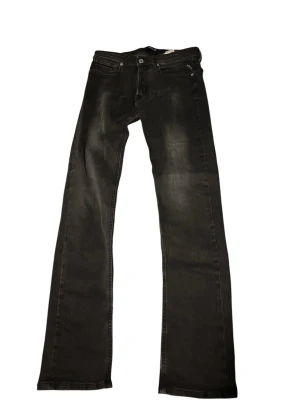 Svarta bootcut jeans från replay - Säljer ett par svarta bootcut jeans från replay med klassiska fem fickor och diskreta slitningar. Jeansen har en något utsvängd passform nedtill och är tillverkade i denim med snygg tvätt. Perfekta för dig som gillar en avslappnad men ändå stilren look.