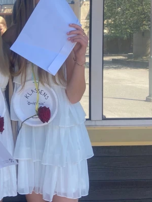 Vit volangklänning med tunna axelband - Hej! Jag säljer min vita klänning med volanger. Den är endast använd en gång, har inga defekter och är i mycket bra skick. Köpt från Vila och är i storlek 38. Klänningen passar perfekt till skolavslutningar eller fina sommardagar. 😇💓🌸🌷