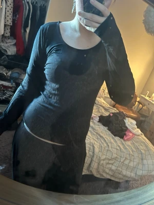 Svart långärmad klänning - En svart, figurnära klänning med lång ärm och rund halsringning. Klänningen har en enkel och stilren design som passar perfekt för dig som gillar minimalistiskt mode. Materialet känns mjukt och stretchigt, vilket ger en bekväm passform.