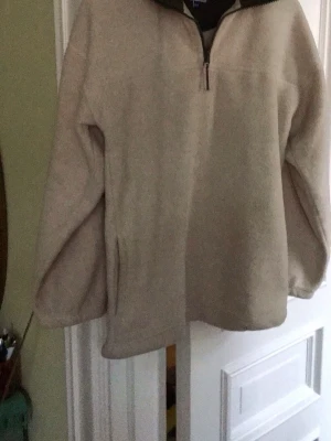 Beige fleece från Rebel Active - Mysig beige fleece med halv dragkedja från Rebel Active. Tröjan har hög krage med mörkare kontrastfärg och är tillverkad i mjukt fleecematerial. Perfekt för kyliga dagar och enkel att dra på över en t-shirt.