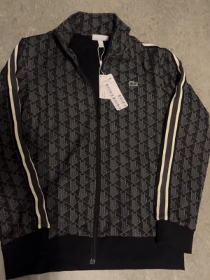 Lacoste monogram - Helt ny och oandvänd Lacoste zipper storlek L men lite liten i storleken så passar typ M