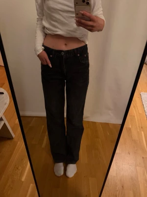 Svarta raka jeans med hög midja - Säljer ett par svarta jeans med rak passform och hög midja. Jeansen har klassiska fem fickor och knappgylf. Materialet är denim i bomull och de har en avslappnad look som passar till det mesta.