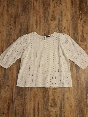 Vit broderad blus med trekvartsärm - Söt vit blus från Lindex med broderade hål och rund halsringning. Blusen har trekvartsärmar och en rak passform. Perfekt för en fräsch och somrig look. Tillverkad i ett lätt och luftigt material som känns skönt mot huden.
