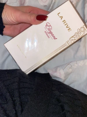 La Rive Elegant Woman parfym - La Rive Elegant Woman är en parfym i en stilren vit förpackning med guldiga detaljer och elegant rosa text. Förpackningen har en lyxig känsla och passar dig som gillar feminina och klassiska dofter. Eau de Parfum.