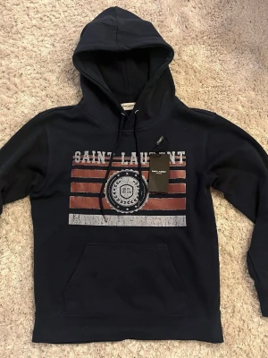 Saint Laurent hoodie! 💙 - Hej, jag gör en Intresskoll på min mörkblåa saint Laurent hoodie i storlek s! Skriv till mig ifall ni är intresserad utav ett köp! Han på bilden är ca 170! 65kg. Rekommenderar att vara mellan 165-175 beroende på vikt osv! Kom med bud ifall du är intresserad. Prislapp finns! 🤩