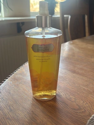 Victoria's Secret Hello Darling mist - Fräsch body mist från Victoria's Secret i doften Hello Darling med inslag av vit nektarin och pion. Flaskan är genomskinlig med gul vätska och har en guldig spraytopp. Rymmer 250 ml och har en snygg, feminin design.