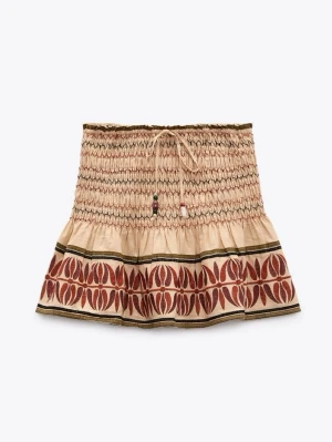 Beige kortkjol med mönster och snörning - Superfin eftertraktad kjol från Zara. beige kortkjol med elastisk midja och snörning framtill. Kjolen har ett unikt rödbrunt mönster längs nederkanten 