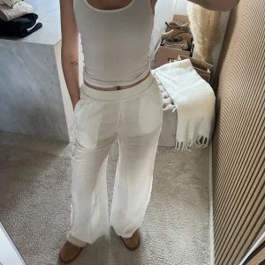 Vita vida linnebyxor från BERSHKA  - Säljer ett par vita linnebyxor med avslappnad passform och resår i midjan. Byxorna har raka, vida ben och är tillverkade i ett tunt, luftigt linnematerial. Perfekta för en stilren och bekväm look.