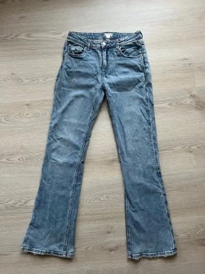Blå bootcut jeans från Gina Tricot - Ett par klassiska blå bootcut jeans från Gina Tricot med fem fickor och låg midja. Jeansen har en snygg tvättad look och är tillverkade i denim med lätt stretch. Perfekta för en avslappnad och trendig stil. Från gina young men passar som en 36!