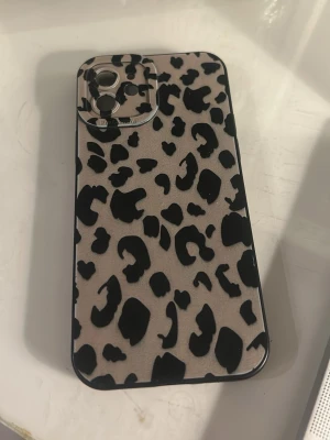 Leopardmönstrat mobilskal svart/beige - Snyggt mobilskal med leopardmönster i svart och beige. Skalet har en matt yta och är gjort i ett tåligt plastmaterial. Passar till mobil med trippelkamera. Perfekt för dig som vill ha ett trendigt och djurinspirerat skydd till din telefon. TILL IPHONE 11