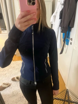 Lululemon define jacket i mörkblå - Lululemon define jacket i mörkblå med silvriga detaljer. Jackan är figursydd och perfekt för träning! Jackan är använd fåtal gånger och i väldigt fint skick. 