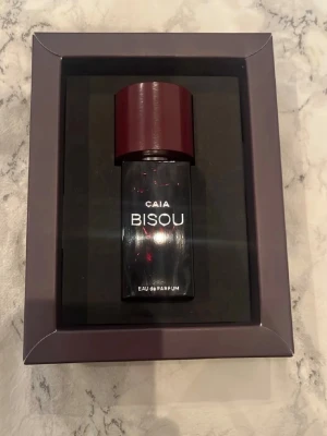 CAIA Bisou Eau de Parfum 50ml (oanvänd) - Säljer en elegant parfym från CAIA, modellen Bisou.Kombinationen av feminin dragningskraft och självsäkerhet, “Bisou” är en förstklassig blandning av citrus och blommor på en varm, träig bas. Livliga toner av mandarin, kardemumma, svart te och patchouli skapar en tidlös doft som är mörk och kryddig, men ändå frisk och aromatisk. Toppnoter: Bergamott, Mandarin, Kardemumma Hjärtnoter: Ros, Svart te, Jasmin Basnoter: Cederträ, Patchouli, Bärnsten, Mysk 50ml (Helt oanvänd) nypris: 595kr.