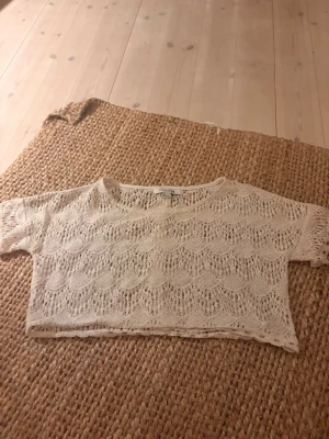 Beige spets croppad topp Forever21 - Säljer en croppad topp från Forever21 i beige spets med korta ärmar. Toppen har ett fint spetsmönster och är perfekt för dig som gillar en luftig och trendig stil. Passar snyggt över ett linne eller bikini.