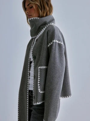 Grå kappa  - Snygg grå kappa/kofta med fina vita detaljer längs kanterna och fickorna. Den kommer även med en matchande halsduk som på bilden. Den passar perfekt nu till vår och sommar! Nypris 799kr
