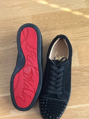 Svarta Louboutin sneakers med nitar - Säljer ett par svarta sneakers från Christian Louboutin med klassisk röd sula och svarta nitar på tån. Extra nittar finns och följer med! Har använts 1-2 gånger skicket är som en ny, säljs då dom har lite för små på mig som har storlek 42. Skorna är i storlek 41 EU. Perfekt inför kommande varma vädret! Pris går att diskutera va inte blyga! 
