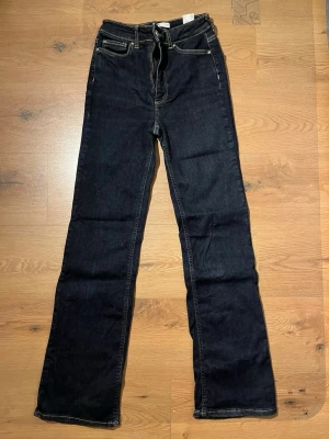 Mörkblå bootcut jeans från Cubus - Säljer ett par mörkblå bootcut jeans från Cubus med klassisk femficksdesign och kontrastsömmar. Jeansen har normal midja och är tillverkade i denim med stretch. Perfekta för dig som gillar en tidlös och snygg look.