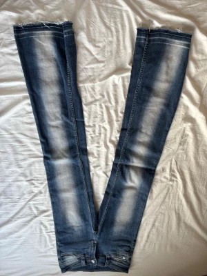White washed blå bootcut jeans - Säljer ett par blå bootcut jeans med snygg slitning, och uppsprätt ner till. Jeansen har klassisk femficksdesign och är tillverkade i stretchigt denimtyg för skön passform. 