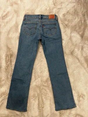 Levi's blå bootcut jeans - Jeansen har en bootcut passform och är i modellen ”superlow boot”. De är aldrig använda, är i storlek 27/32. Helt nya. Pris kan diskuteras vid snabb affär. Säljer bara för jag behöver rensa min garderob. Skriv bara om ni har några frågor eller vill ha fler bilder!!💗