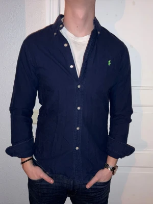 Mörkblå skjorta från Ralph Lauren - Mörkblå skjorta från Ralph Lauren i storlek S.  Fint skick till ett bra pris. Nypris: 1995kr. Mitt pris: 349kr. Vid frågor eller funderingar, tveka inte att höra av dig.