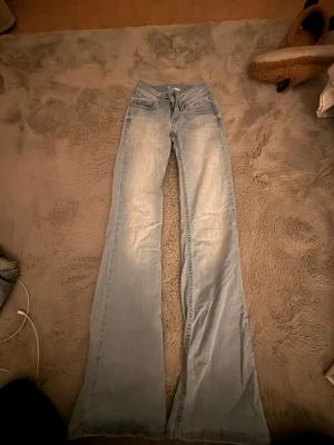 Ljusblå bootcut jeans från Miss Sixty - Säljer ett par ljusblå bootcut jeans från Miss Sixty med klassisk femficksdesign och broderade bakfickor. Jeansen har låg midja och är tillverkade i denim med lätt tvättad look. Perfekta för dig som gillar retrostil och vill sticka ut.