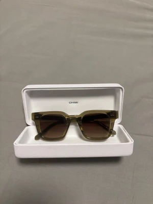 CHIMI 04 Gröna - Snygga solglasögon från CHIMI med fyrkantig form och transparent brun båge. Bågarna har en stilren design som passar till många looks. Kommer i original vit hård förvaringsbox.