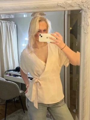 Ljusrosa omlottblus från Vila - Säljer en ljusrosa omlottblus från Vila med korta ärmar och knytband i midjan. Blusen har en v-ringning och är tillverkad i ett lätt och flowigt material som ger en snygg och avslappnad look.🥰🥰💕