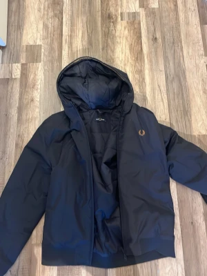 Mörkblå pufferjacka från Fred Perry - Säljer en mörkblå pufferjacka från Fred Perry. Perfekt för kalla dagar och riktigt snygg nu till våren för en lite schysstare stil 💫 säger M men passar mer som en S