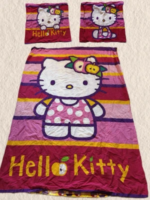Hello Kitty påslakanset  - Säljer ett färgglatt Hello Kitty påslakanset med två örngott och ett påslakan. Motivet är Hello Kitty i prickig klänning med frukt i håret, på rosa, lila och gula ränder. Materialet är mjuk bomull, perfekt för dig som gillar söta och lekfulla sängkläder.