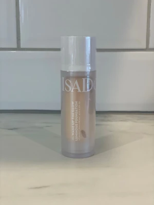 IsaDora Wake Up The Glow Foundation - IsaDora Wake Up The Glow Luminous Foundation i en ljus beige nyans. Kommer i en cylinderformad plastflaska med vit kork och tydlig logga. Ger ett naturligt glow och passar dig som vill ha en fräsch bas med lyster.