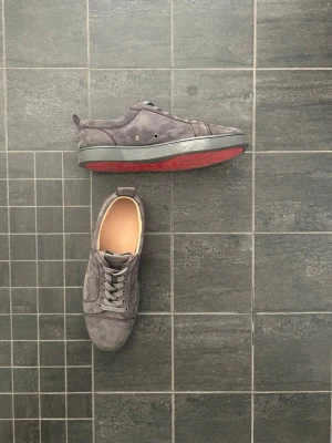 Gråa Loubs - Stilrena sneakers i grå mocka av märket Louboutin. Den perfekta sommarsneakern att ha, med en snygg look och en superb passform.