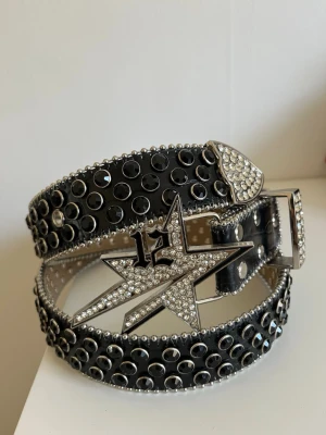 Svart Rhinestone bälte - Svart skärp från Lukamachain med rhinestones och silverfärgade nitar.   Märke: Lukamachain Detaljer: Rhinestones och metallnitar Skick: Mycket fint skick, använt 3 gånger. 110 cm, M i storlek.