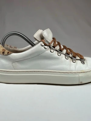 Diemme - Unika vita sneakers med bruna skosnören och metallhål för snörning. Skorna har pälsdetalj vid hälen och är tillverkade i läder. Snygg och modern design som sticker ut med sina outdoor-inspirerade detaljer.