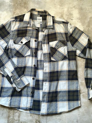 Rutig skjorta från Dobber - Snygg rutig skjorta från Dobber i blått, vitt och beige. Skjortan har två bröstfickor med knappar, klassisk krage och långa ärmar med manschetter. Tillverkad i mjuk bomull, perfekt för en avslappnad stil.