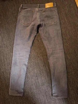 Slim fit grå jeans från tiger of sweden - Slim fit jeans i grå denim från tiger of sweden, tillverkade i Italien. Klassisk femficksmodell med raka ben och snygga sömdetaljer baktill. Perfekta för dig som gillar en stilren och modern look.