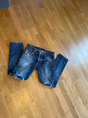 Blå slitna jeans med hål - Ett par feta nudie thin Finn jeans. Galna honey Combes och washes. Står storlek L32 men mer som L30, är 90cm långa och har 38cm midja. Skriv vid minsta fråga eller bud!