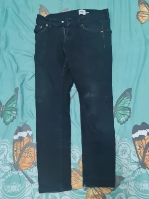 Svarta raka jeans från H&M - Säljer ett par svarta jeans från H&M med klassisk femficksmodell och raka ben. Jeansen har bälteshällor, knappgylf och subtila kontrastsömmar. Perfekta till en avslappnad streetwear-look.