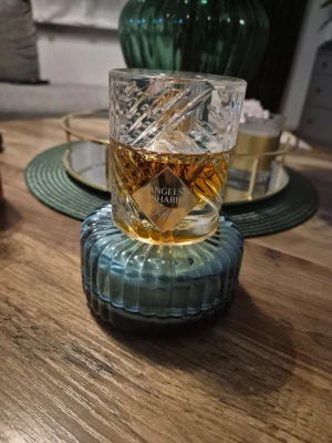 By Kilian Angels' Share Eau de Parfum - Lyxig parfym från By Kilian, Angels' Share, i en elegant och tung glasflaska med mönstrad design. Flaskan är transparent med guldtonad vätska och har en blågrön botten. Perfekt för dig som gillar exklusiva dofter och snygg inredningsdetalj.