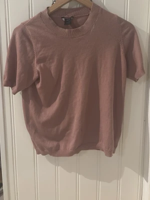 Rosa kortärmad topp  - En enkel och stilren rosa topp från Lindex med rund halsringning och korta ärmar. Tillverkad i mjukt material som känns skönt mot huden. Perfekt att matcha med jeans eller kjol för en avslappnad look.