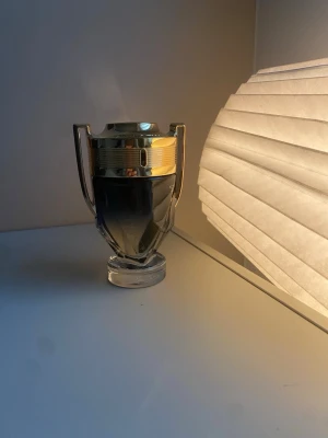Paco Rabanne Invictus parfym 100 ml - Snygg parfymflaska från Paco Rabanne i form av en pokal med guldfärgade detaljer och transparent glas. Flaskan har en modern och sportig design som verkligen sticker ut på hyllan. Perfekt för dig som gillar exklusiva och unika dofter.