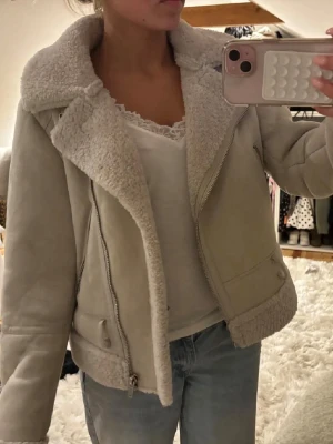 Beige teddyjacka med dragkedja - Snygg beige teddyjacka med stora slag och mysigt foder. Jackan har dragkedja framtill, fickor på sidorna och detaljer i samma färg. Perfekt för kalla dagar och ger en trendig look till din outfit. Perfekt för vår och höst🩷