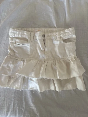 Jeans kjol  - Vit jeans kjol med volang från Gina tricot. Storlek xs, säljer då den inte passar mig som i vanliga fall när 34/36 i jeans och kjolar. Skulle säga att den passar en xs/32. Aldrig annänd