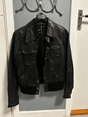 Svart skinnjacka från Lindex - Skinnjacka. Några fläckar vid kragen och på jackan som ni ser på bilderna men det går säkert bort med en tvätt. Jag testade skrapa bort det och det gick! Använt 2 gånger. Passar XS, S, M, L? Sitter skönt och är rätt varm så kan användas när som!
