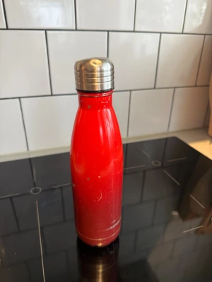 Röd metallvattenflaska Le Creuset  - Snygg röd vattenflaska i metall från Le Creuset med silverfärgat skruvlock. Flaskan har en slimmad form och passar perfekt i väskan eller träningsväskan. Praktisk för både skola och utflykter.