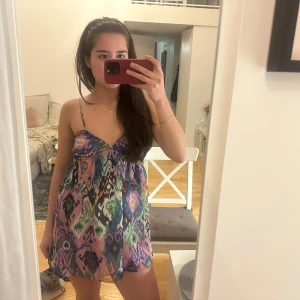 Färgglad kortklänning med mönster, zara - Säljer en multifärgad kortklänning med tunna axelband och ett unikt mönster i blått, rosa, grönt och svart. Så somrig och snygg!!!