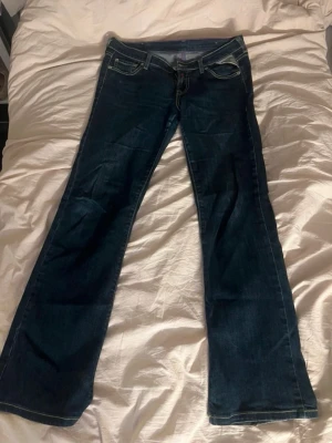 Mörkblå bootcut jeans från Replay - Snygga mörkblå bootcut jeans från Replay med kontrastsömmar och dekorativa bakfickor. Klassisk femficksmodell och låg midja. Perfekta för dig som gillar en avslappnad men trendig look.