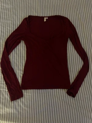Mörkröd långärmad topp från Nelly - Snygg mörkröd långärmad topp med u-ringning. Bara haft en gång men haft den i garderoben ett tag.