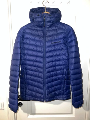 Blå dunjacka från Peak Performance - Peak Performance Frost dunjacka med huva i blå farg, storlek S. Jackan ar i mycket bra skick och sparsamt använd, utan fläckar eller skador. Lätt och varm dunjacka i slitstarkt Pertex-material, perfekt för både vardag och friluftsliv. En klassisk och tidlös modell. Finns att hämta i Södertälje eller Örebro.