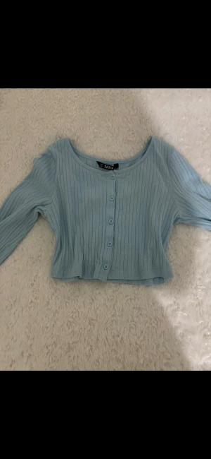 Ljusblå ribbad kofta/magtröja - Säljer en ljusblå ribbad kofta/magtröja från SHEIN med långa ärmar och knappar framtill i storlek xs. Kortare modell med rund halsringning och smal passform.💙💙🦋
